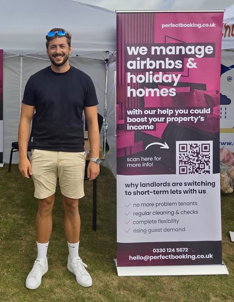 Ollie Laing, founder of Perfect Booking, at the Perfect Booking stand next to a banner reading We manage Airbnbs and holiday homes