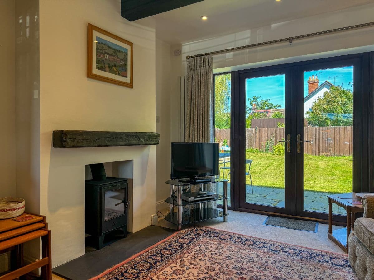 A sitting room with a wood burner and garden doors