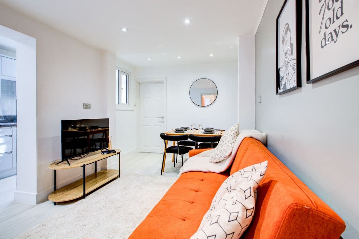 An open-plan living room with an orange sofa and dining table